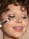 A person using the Blending Brush to apply eyeshadow and highlighter.