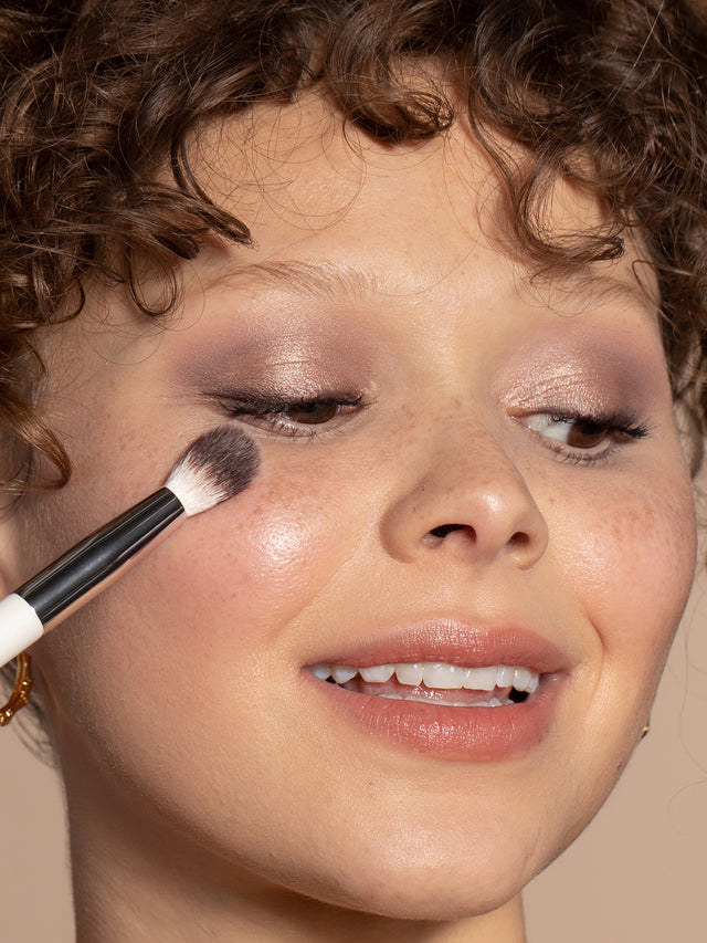 A person using the Blending Brush to apply eyeshadow and highlighter.