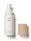 ILIA soft foaming cleanser bottle with its beige cap placed beside it.