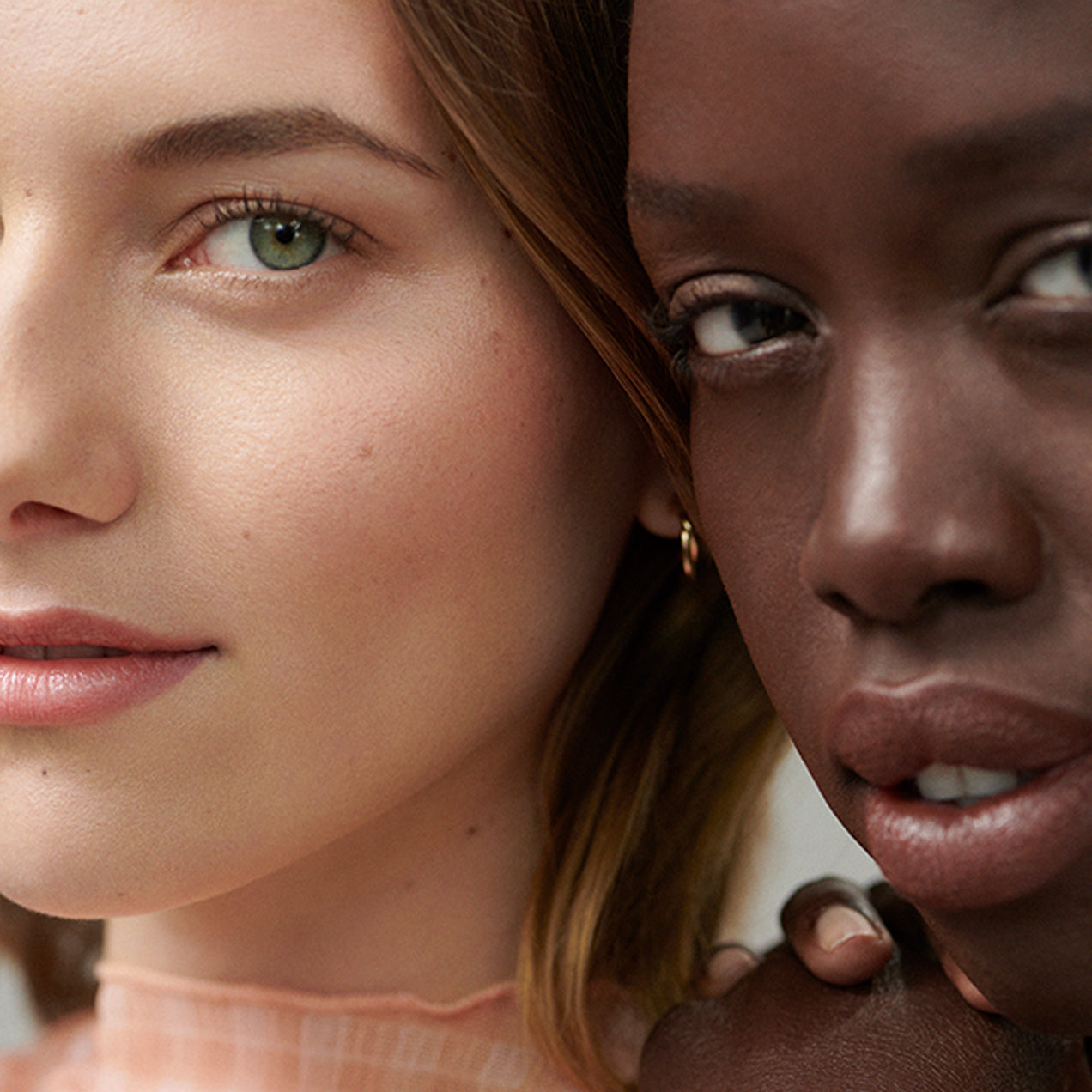Two models with balanced complexions and make up on gazing into the camera.