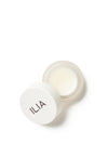 A compact jar of nourishing balm with a sleek white lid featuring the ILIA logo.