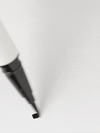 GIF of a white ILIA Liquid Eyeliner with a fine black felt tip drawing  on a surface.