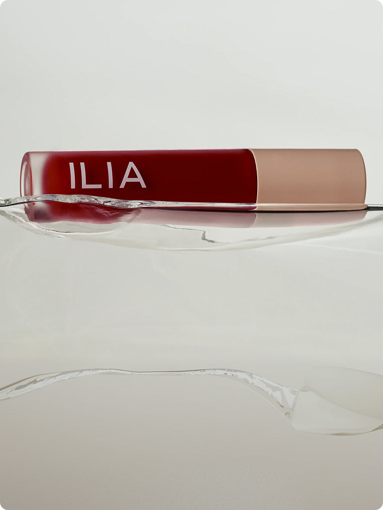 Red ILIA lip gloss on water to showcase the hydrating ingredients