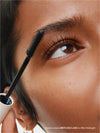 Close-up of a person applying mascara to their eyelashes with a brush.