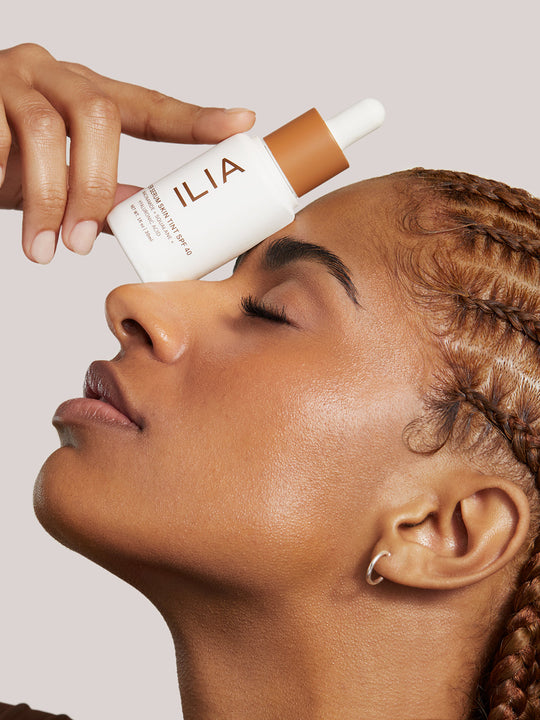 Image of Super Serum Skin Tint bottle next to the dropper applicator. Image includes seals for Allure Best of Beauty Award, Byrdie Eco Beauty Award, and the 1% for the Planet Member