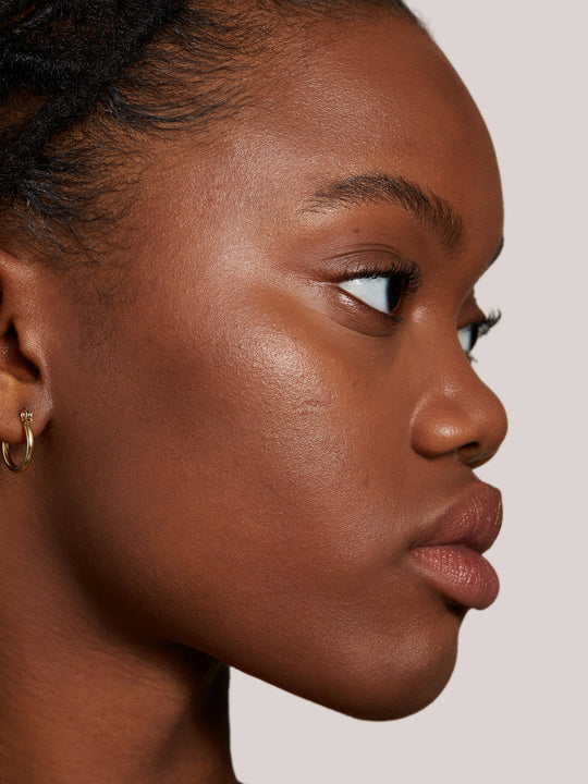 Image of Super Serum Skin Tint bottle next to the dropper applicator. Image includes seals for Allure Best of Beauty Award, Byrdie Eco Beauty Award, and the 1% for the Planet Member
