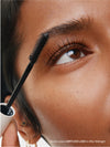 Close-up of a person applying mascara to their eyelashes with a brush.